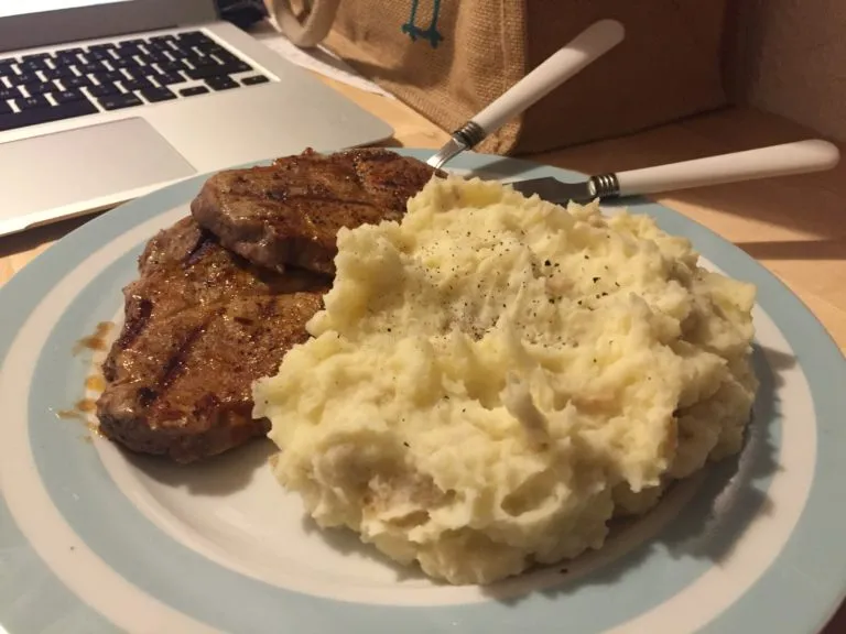 Photograph of a plate with steak and mashed potatoes, sprinkled with a little pepper.